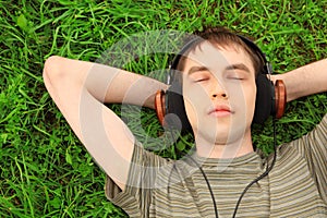 Teenager lies on grass in headphones