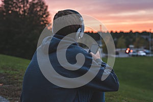 Teenager listening to music and watching the sunset.