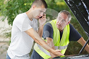 teenager making phonecall after car breaks down with dad