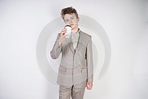 Teenager male in gray business suit with paper Cup of coffee in hand on white studio background