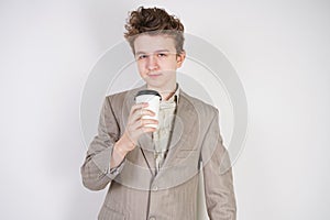 Teenager male in gray business suit with paper Cup of coffee in hand on white studio background