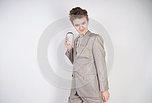 Teenager male in gray business suit with paper Cup of coffee in hand on white studio background