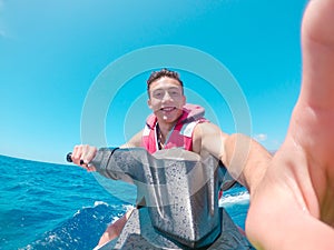 Teenager man enjoying summer in a jet ski in the middle of the sea having fun racing alone and isolated