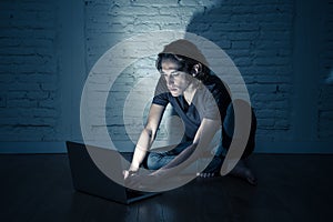 Teenager man suffering Internet cyber bullying sitting alone with computer feeling hopeless