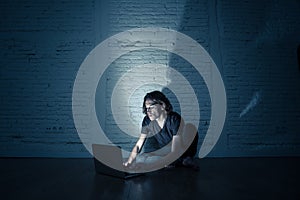 Teenager man suffering Internet cyber bullying sitting alone with computer feeling hopeless