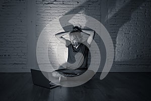 Teenager man suffering Internet cyber bullying sitting alone with computer feeling hopeless