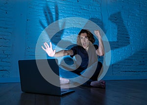 Teenager man suffering Internet cyber bullying sitting alone with computer feeling hopeless