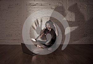 Teenager man suffering Internet cyber bullying sitting alone with computer feeling hopeless