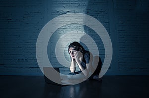 Teenager man suffering Internet cyber bullying sitting alone with computer feeling hopeless