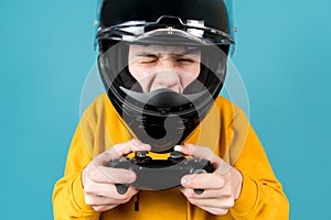 A teenager in a motorcycle helmet with a joystick from a game console winks