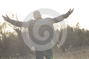Teenager in open field with arms raised