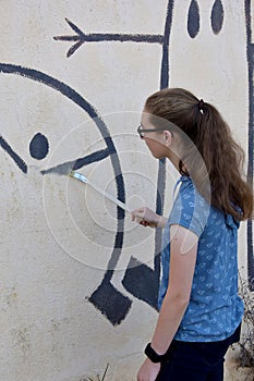 Teenage girl repairs wallpainting photo