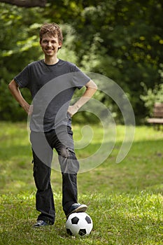 Teenager play soccer player. Boy with ball on green grass