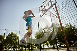 Teenager player throwing ball into basketball hoop