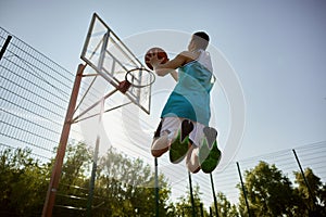 Teenager player throwing ball into basketball hoop, shot in motion