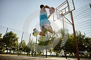 Teenager player throwing ball into basketball hoop, shot in motion, bottom view