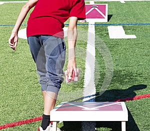 Teenager playing corn hole throwing two bean bags