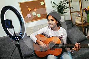 Teenager playing guitar and recording vlog and music tutorial for the Internet