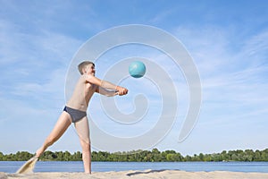 A teenager playing volleyball on the beach on a sunny day.  Active  lifestyle