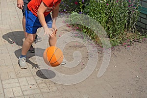 Teenager plays basketball with his father. Closeup view with no faces. Boy and man bounce the ball on a backyard. Sport fans at