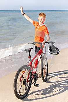 Teenager is posing with bicycle on a background of the sea.