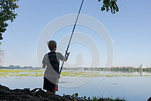 A teenager prepares to go fishing on the river. Sport fishing on the river in summer