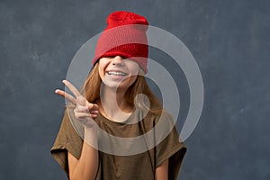 Teenager pulling down red hat, keeping eyes closed
