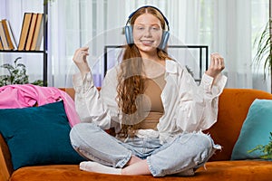 Teenager red hair girl breathes deeply with mudra gesture, eyes closed, meditating, listening music