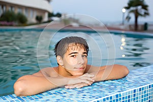 Teenager relaxing near ledge in pool open-air