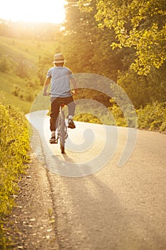 Teenager riding a bicycle on the road summer sunlit