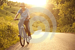 Teenager riding a bicycle on the road summer sunlit