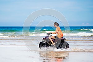 Teenager riding quad bike on beach