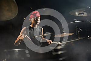 Teenager rock band drummer . cool and talented Asian American mixed ethnicity teenage boy playing drums in headband performing