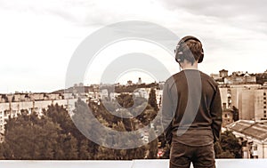 Teenager on the roof of the house in the headphones