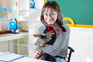 Teenager of school with funny dog against chalkboard. School girl with puppi in glasses smiling. Go back to school