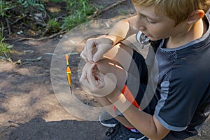 A teenager sets up a lure to catch fish. Sport fishing on the river in summer