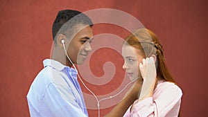 Teenager sharing earphones with girlfriend listening to favorite lyric song