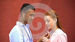 Teenager sharing earphones with girlfriend listening to favorite lyric song