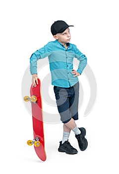 A teenager in a shirt, shorts and a baseball cap stands holding a red skateboard in his hand, isolated on a white background.