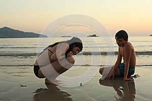 Teenager siblings on seaside beach looking for shell crab and corall pieces