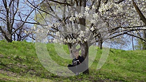Teenager sits under tree and writes poem