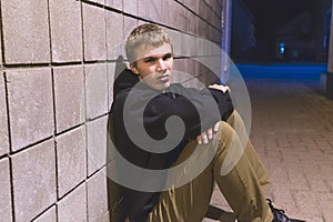 Teenager sitting in an alleyway.