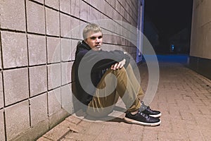 Teenager sitting in an alleyway.