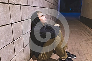 Teenager sitting in an alleyway.