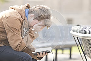 Teenager sitting on bench reading Bible and praying