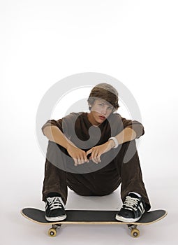 Teenager sitting with feet on skateboard