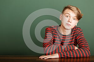 Teenager sitting on green background