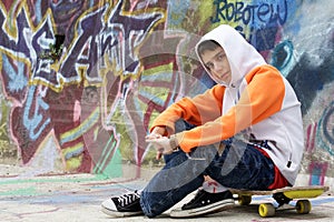 Teenager sitting near a graffiti wall