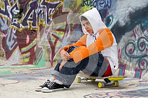 Teenager sitting near a graffiti wall