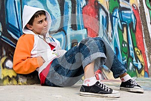 Teenager sitting near a graffiti wall